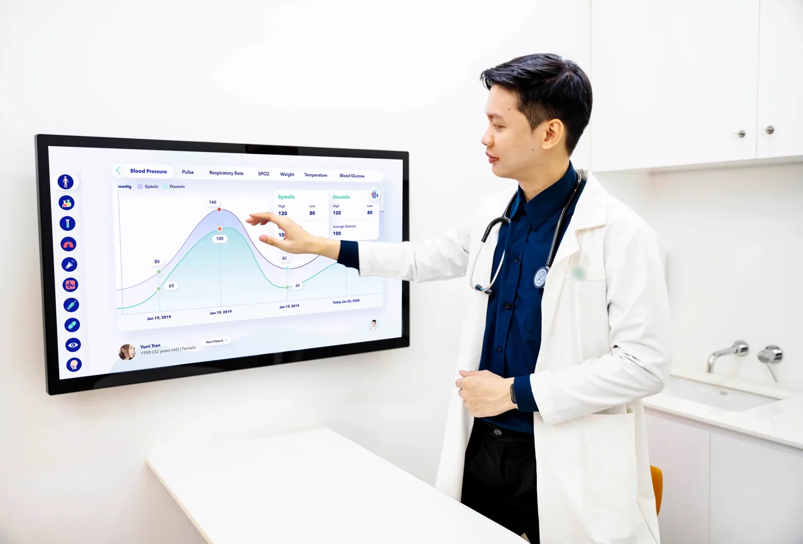 A doctor reviewing a blood pressure chart on a wall display